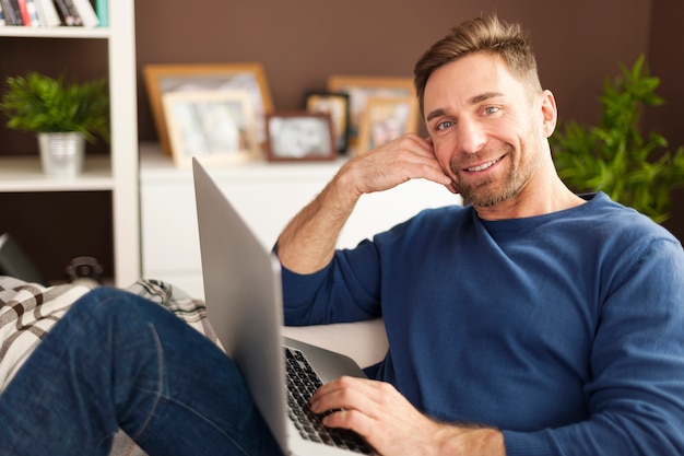 Portret van glimlachende man met laptop op bank