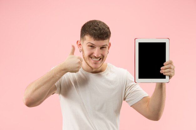 Portret van glimlachende mens die op laptop met leeg scherm richt dat op roze studioachtergrond wordt geïsoleerd. en reclame concept.