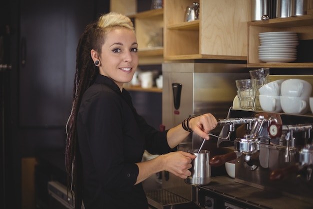 Portret van glimlachende serveerster die de koffiemachine met behulp van