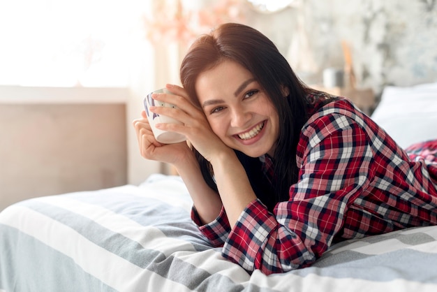 Gratis foto portret van glimlachende vrouw die van ochtend in bed genieten