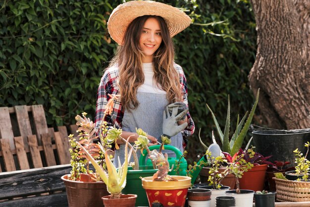 Portret van glimlachende vrouwelijke tuinman die zich in tuin bevindt