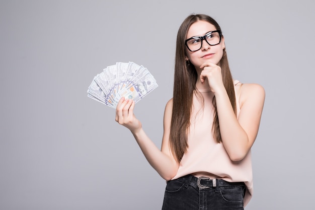 Portret van het glimlachen de dollars van de vrouwenholding over grijze muur worden geïsoleerd die