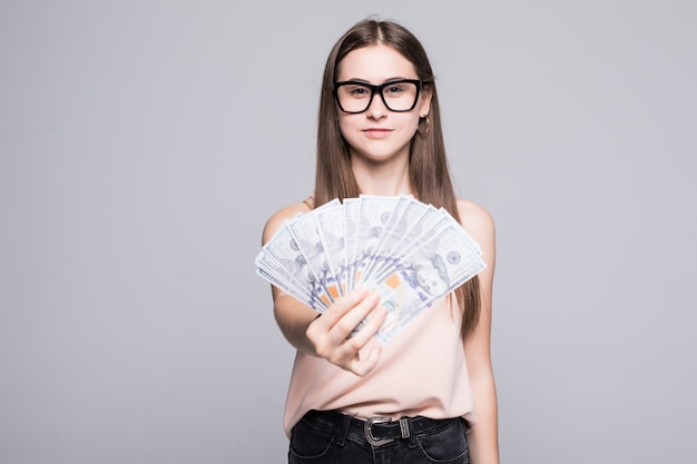 Portret van het glimlachen de dollars van de vrouwenholding over grijze muur worden geïsoleerd die