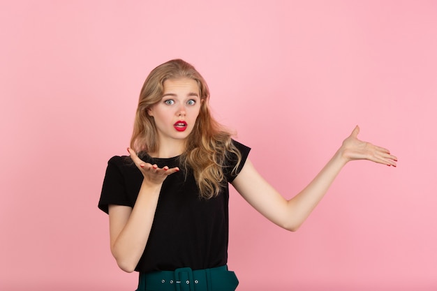 Portret van het jonge emotionele vrouw gesturing geïsoleerd op roze studio