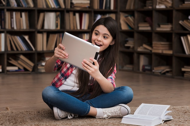 Portret van het jonge meisje spelen op tablet bij de bibliotheek