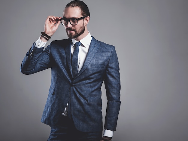 Gratis foto portret van het knappe model van de manierzakenman gekleed in elegant blauw kostuum met glazen