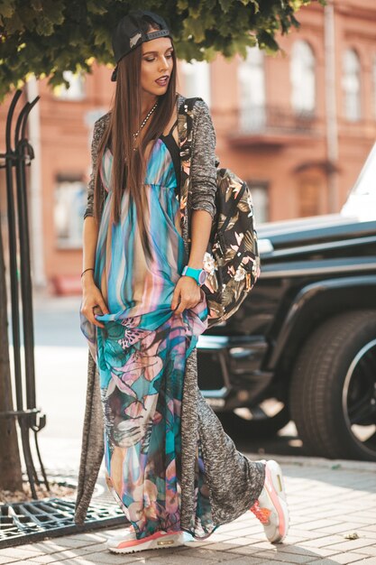 Portret van het mooie model van de glamour donkerbruine tiener in de zomer hipster kleren en zak. Meisje poseren in de straat. Vrouw in cap