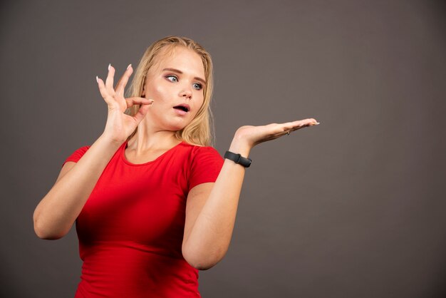 Portret van het mooie vrouw stellen over donkere muur.