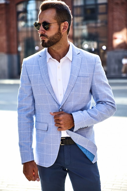 Portret van het sexy knappe model van de manierzakenman gekleed in het elegante blauwe kostuum stellen op straatachtergrond. metrosexual