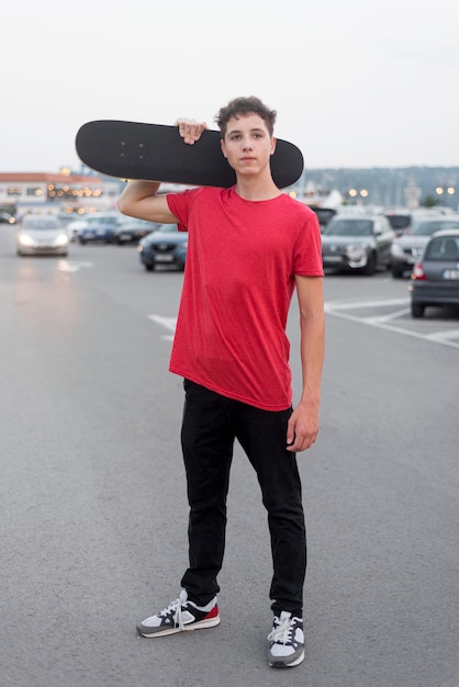 Gratis foto portret van het stijlvolle jonge skateboard van de jongensholding