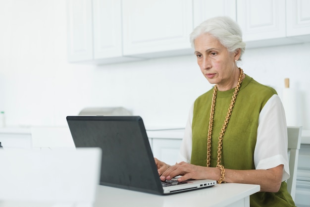 Gratis foto portret van hogere vrouw die laptop met behulp van