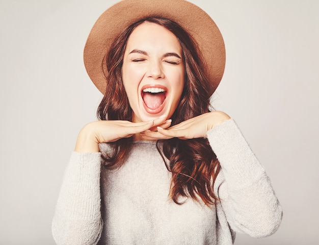 Gratis foto portret van jong modieus het lachen model in grijze toevallige de zomerkleren in bruine hoed met natuurlijke make-up