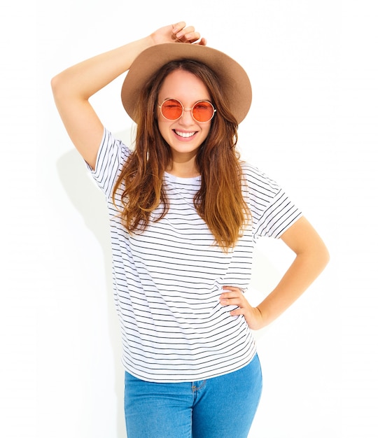 Portret van jong modieus lachend vrouwenmodel in toevallige de zomerkleren in bruine hoed met natuurlijke die make-up op witte muur wordt geïsoleerd. Knipogend