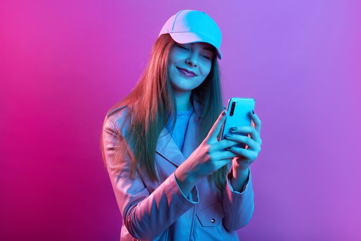 Gratis Foto portret van jong mooi modieus model dat leerbakker en honkbal glb draagt, slimme telefoon in handen houdt