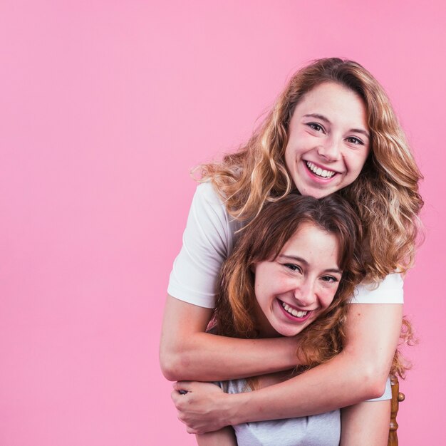 Portret van jong wijfje dat haar vriend koestert tegen roze achtergrond