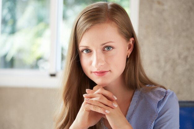 Portret van jonge aantrekkelijke dame die camera met haar dichtgeklemde handen bekijkt