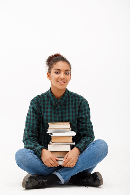 Portret van jonge Afrikaanse vrouw met boeken op wit.