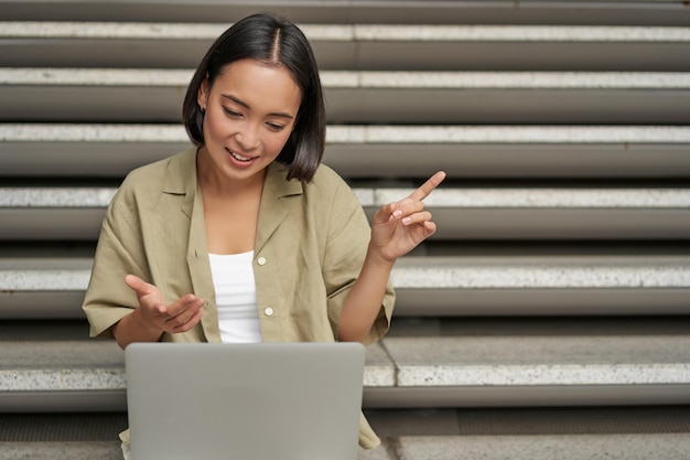 Portret van jonge aziatische studente praat op laptop videochat tijdens online vergadering sitti