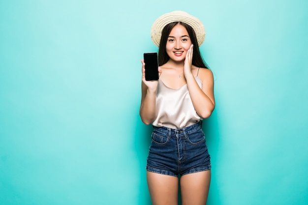 Portret van jonge Aziatische vrouw die haar lege sreen mobiele telefoon toont die over groene achtergrond wordt geïsoleerd.