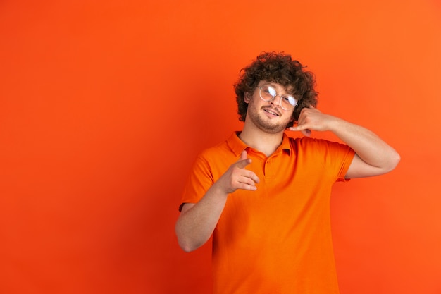 Portret van jonge blanke man met heldere emoties op oranje studio