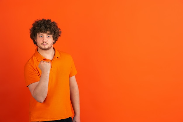 Portret van jonge blanke man met heldere emoties op oranje studio