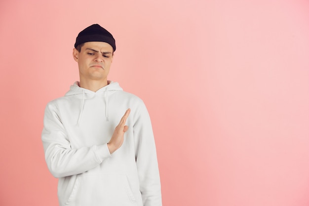 Portret van jonge blanke man met heldere emoties op roze studio achtergrond