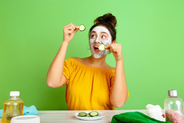 Portret van jonge blanke vrouw in haar schoonheidsdag, huid en haarverzorgingsroutine. Vrouwelijk model met natuurlijke cosmetica gezichtsmasker voor make-up toe te passen. Lichaams- en gezichtsverzorging, natuurlijk schoonheidsconcept.