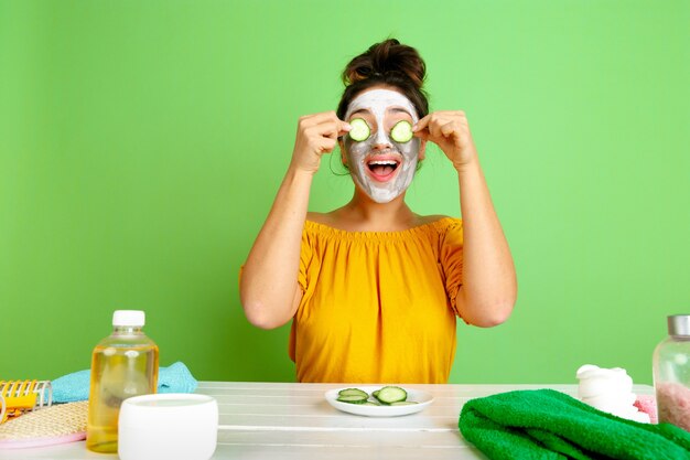 Portret van jonge blanke vrouw in haar schoonheidsdag, huid en haarverzorgingsroutine. Vrouwelijk model met natuurlijke cosmetica gezichtsmasker voor make-up toe te passen. Lichaams- en gezichtsverzorging, natuurlijk schoonheidsconcept.