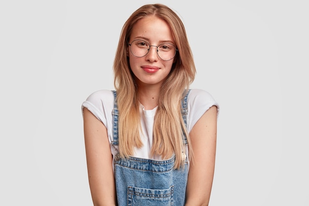 Portret van jonge blonde vrouw, gekleed in denim overall