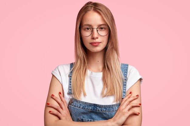 Portret van jonge blonde vrouw, gekleed in denim overall