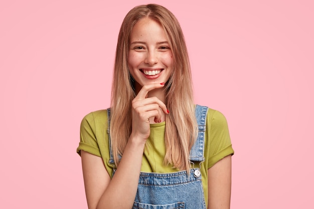 Portret van jonge blonde vrouw, gekleed in denim overall