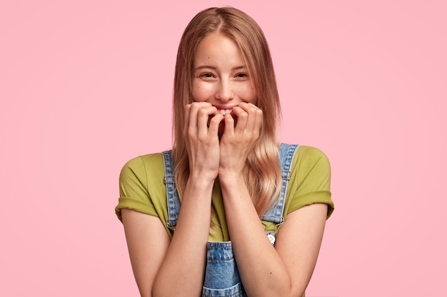 Portret van jonge blonde vrouw, gekleed in denim overall