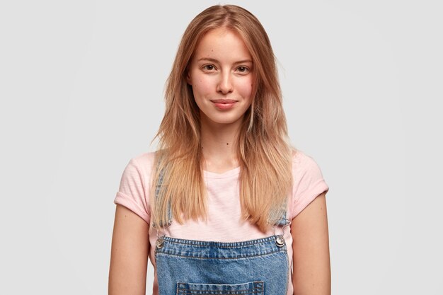 Portret van jonge blonde vrouw in denim overall