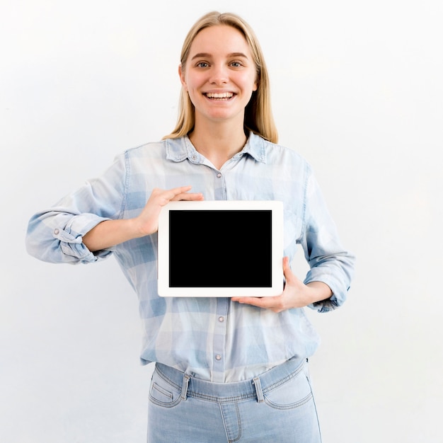 Portret van jonge blondevrouw die een tablet houden