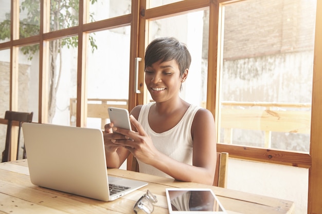 Portret van jonge brunette vrouw zitten in café met laptop