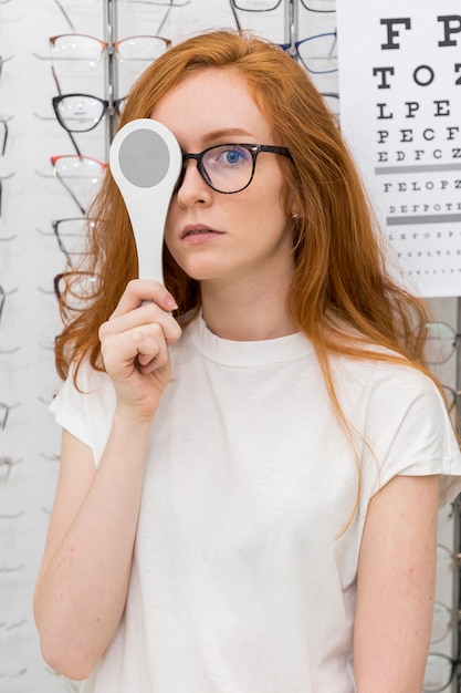 Portret van jonge de optiekoccluder van de vrouwenholding voor haar oog