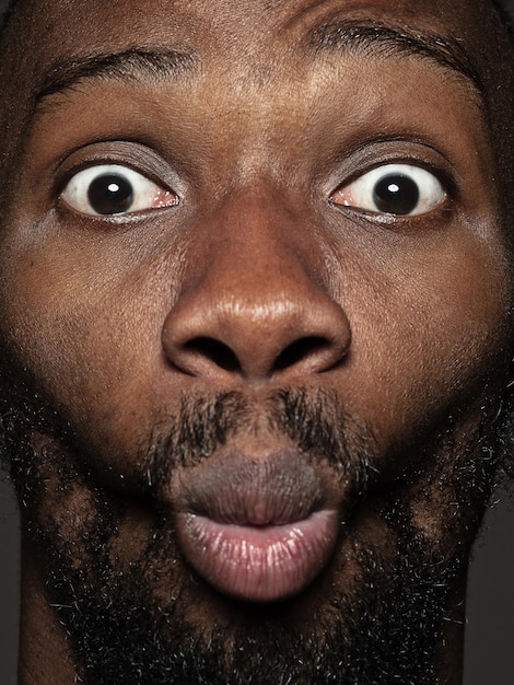 Gratis foto portret van jonge en emotionele afro-amerikaanse man close-up. mannelijk model met verzorgde huid en heldere gezichtsuitdrukking. concept van menselijke emoties. blije grimassen.