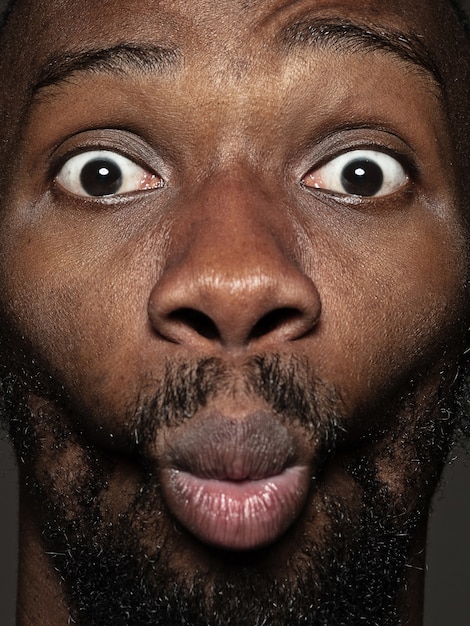 Portret van jonge en emotionele Afro-Amerikaanse man close-up. mannelijk model met verzorgde huid en heldere gezichtsuitdrukking. Concept van menselijke emoties. Blije grimassen.