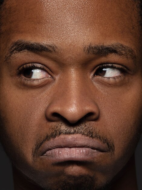 Portret van jonge en emotionele Afro-Amerikaanse man close-up. Zeer gedetailleerde fotoshoot van mannelijk model met verzorgde huid en heldere gezichtsuitdrukking. Concept van menselijke emoties. Attent.