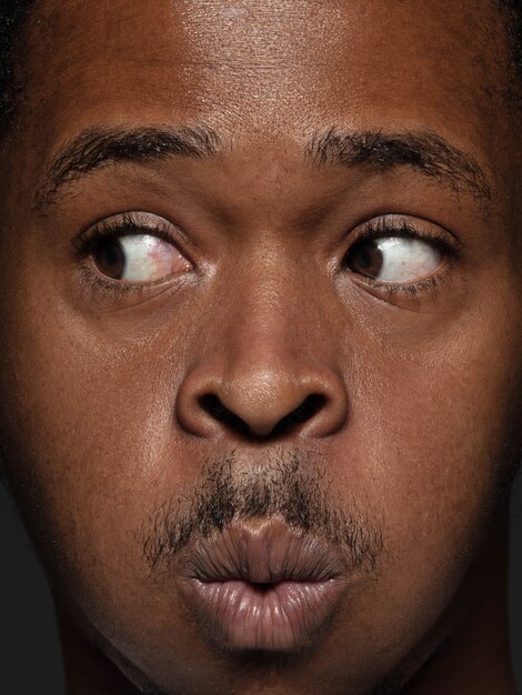 Portret van jonge en emotionele Afro-Amerikaanse man close-up. Zeer gedetailleerde fotoshoot van mannelijk model met verzorgde huid en heldere gezichtsuitdrukking. Concept van menselijke emoties. Kijkend naar de zijkant.