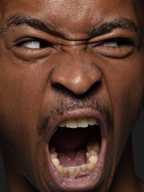 Gratis foto portret van jonge en emotionele afro-amerikaanse man close-up. zeer gedetailleerde fotoshoot van mannelijk model met verzorgde huid en heldere gezichtsuitdrukking. concept van menselijke emoties.