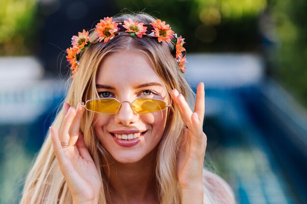 Portret van jonge gelukkige blonde lange haarvrouw in blauwe bikini en bloemkroon op hoofd