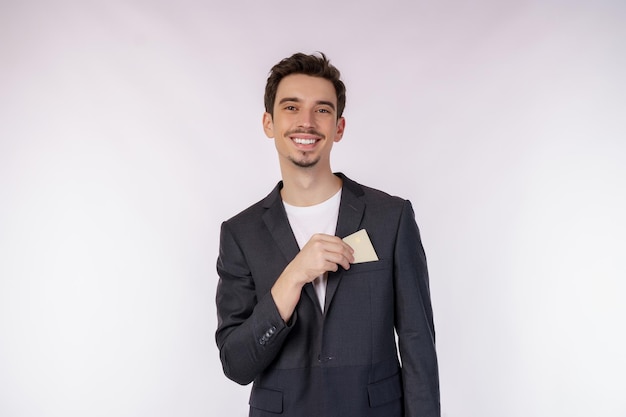 Portret van jonge glimlachende knappe zakenman die creditcard toont die over witte achtergrond wordt geïsoleerd
