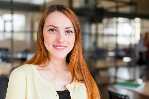 Portret van jonge glimlachende vrouw die camera bekijkt