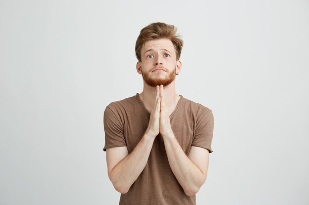 Portret van jonge knappe man met baard bidden hopen.