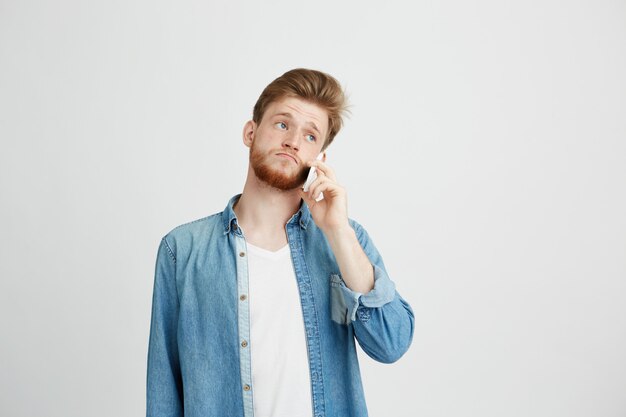 Portret van jonge knappe man met baard spreken op telefoon.