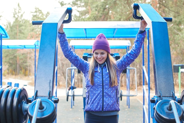 Portret van jonge meisjesatleten die een gezonde sport leiden op de buitenspeeltuin met apparatuur in het bos