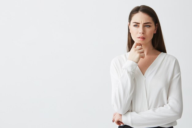 Portret van jonge mooie brunette zakenvrouw dromen denken fronsend. Hand op kin.