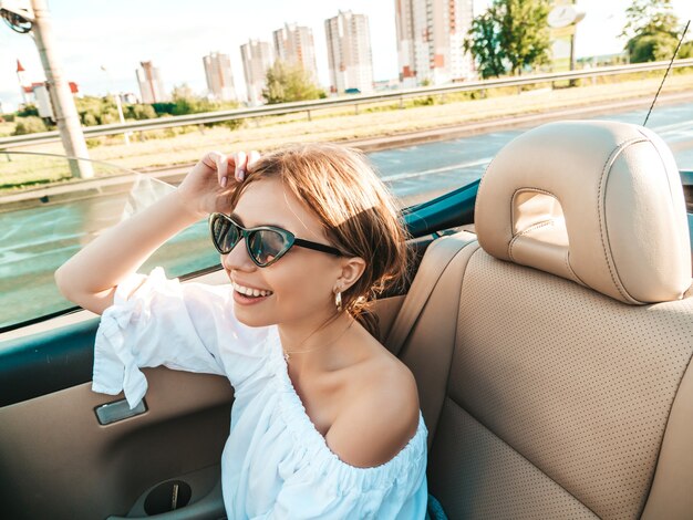 Portret van jonge mooie en lachende hipster vrouw in converteerbare auto