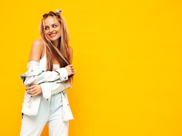 Portret van jonge mooie lachende blonde vrouw in trendy zomerkleren Sexy zorgeloze vrouw poseren in de buurt van gele muur in studio Positief model plezier binnenshuis vrolijk en gelukkig